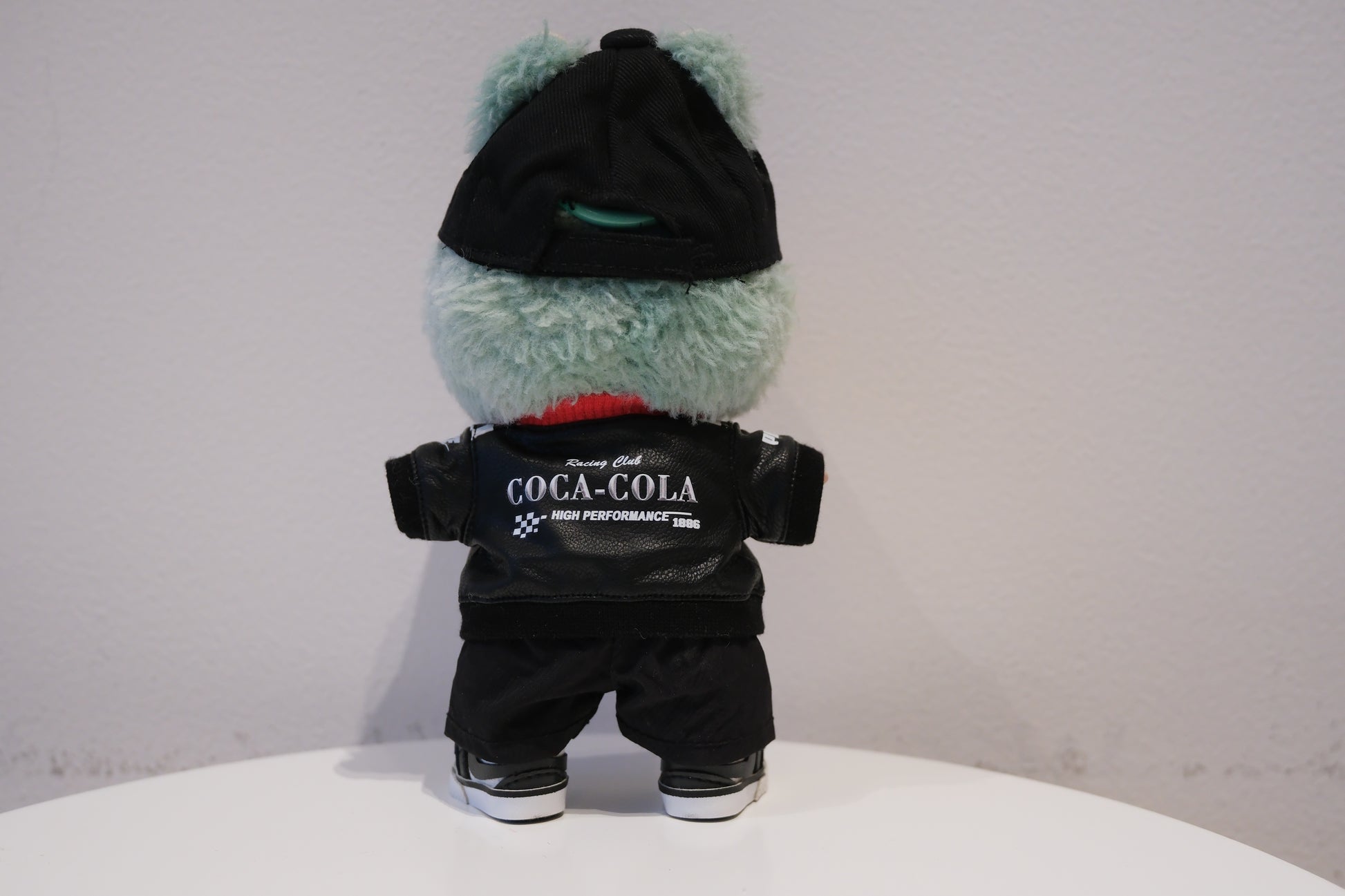 labubu wearing a black outfit with 'Coca-Cola' branding on a white surface.