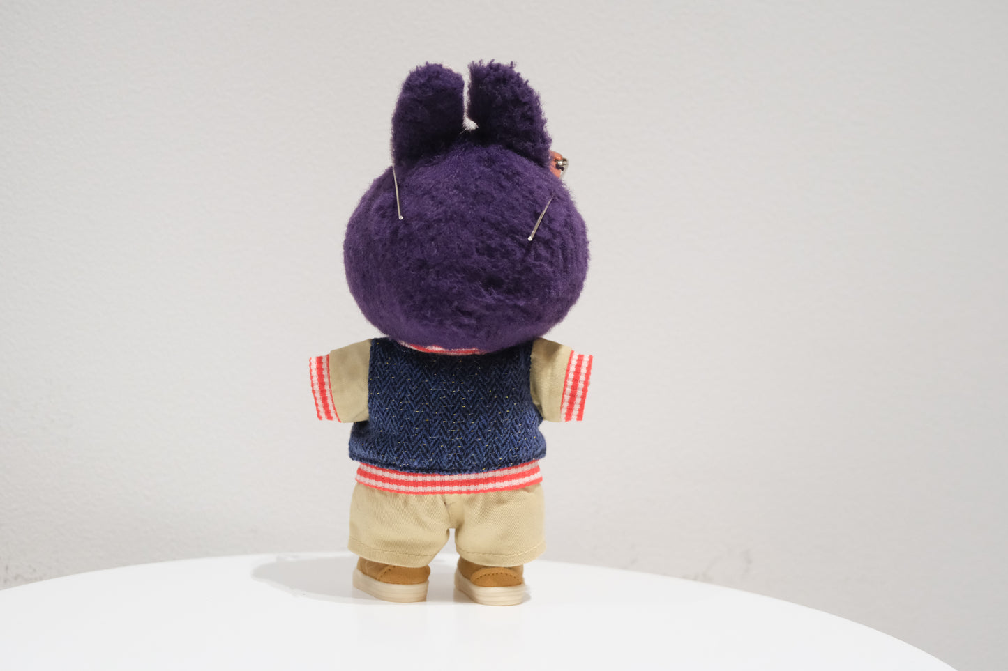 back view of the Labubu figure in the collegiate outfit showing the varsity jacket and khaki shorts.