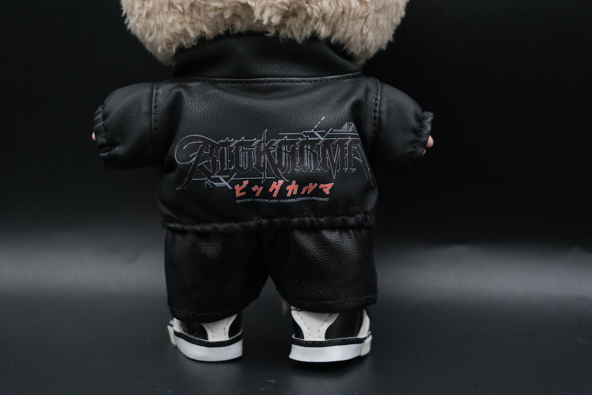 A Labubu designer toy figure in a dark, urban-style outfit, featuring a black leather jacket and pants , sunglasses and a pair of shoes