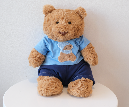 Jellycat Bartholomew Bear wearing a 2-piece cozy casual outfit with a miniature T-shirt and matching pants.