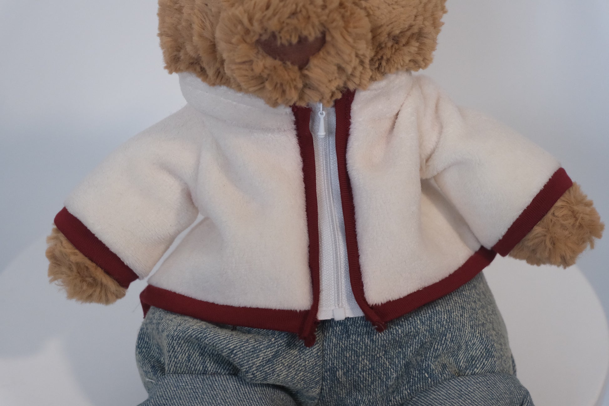 Jellycat Bartholomew Bear plush wearing a 2-piece winter outfit with a cream fleece coat and blue jeans.