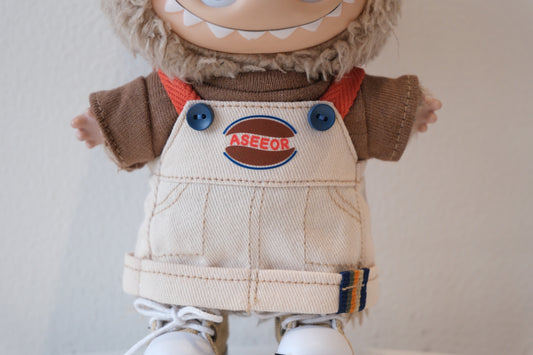 labubu wearing a brown sweater and beige overalls with a logo 