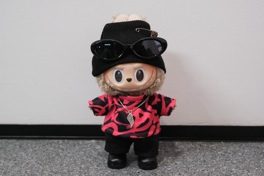 LABUBU plush doll wearing a black beanie with a safety pin, sunglasses, and a pink and black graphic t-shirt