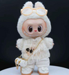 A Labubu doll wearing a white, fuzzy knit sweater with a gold sequin detail and matching white pants