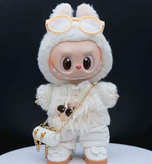 A Labubu doll wearing a white, fuzzy knit sweater with a gold sequin detail and matching white pants