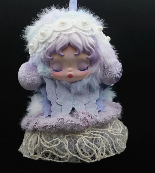 A Skullpanda figure wearing a custom-made, purple butterfly dress and a matching headband.

