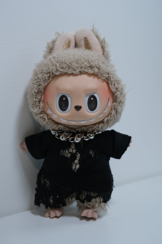 The Monsters figure's silver skull chain necklace over a black fabric dress.
