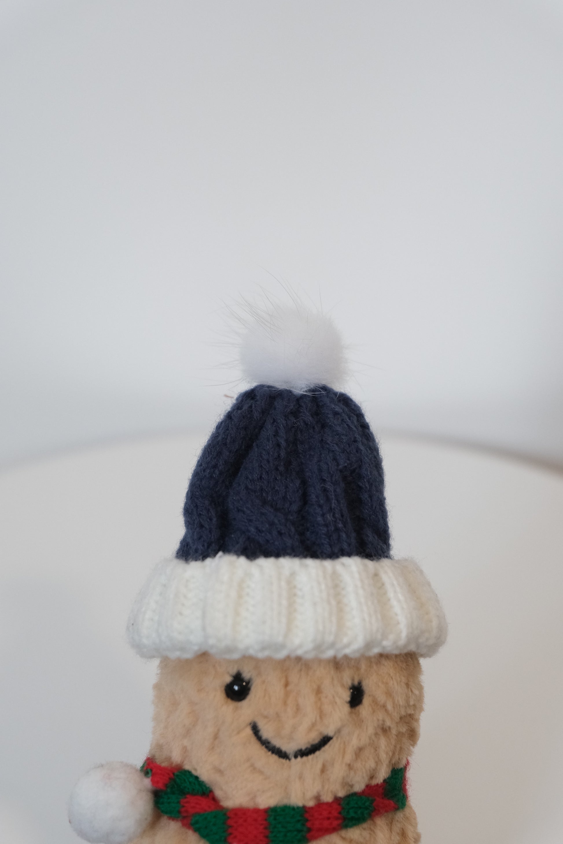 Close-up of the chunky knit hat and scarf texture on the Jellycat Amuseables Peanut plush.