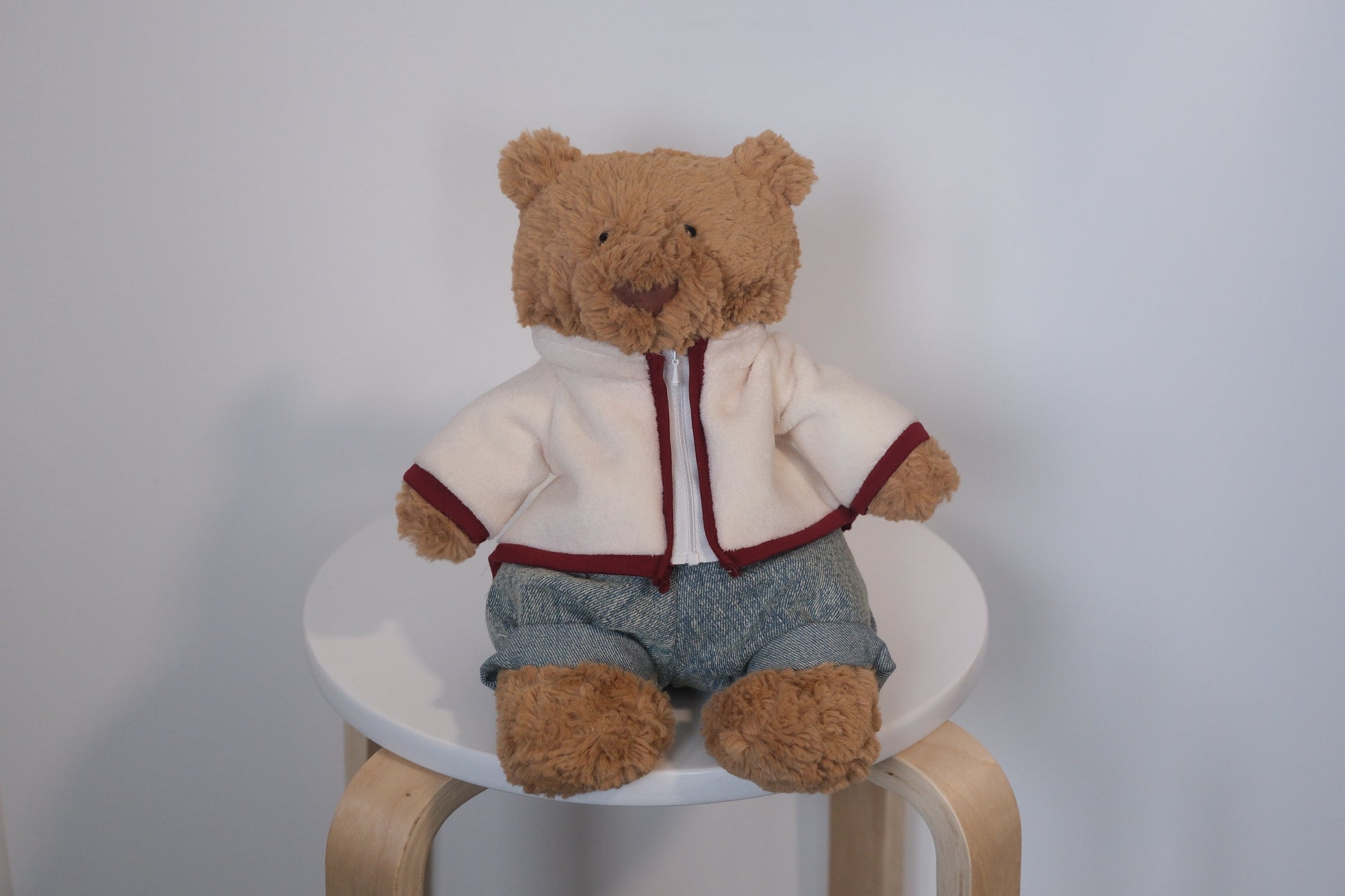Jellycat Bartholomew Bear plush wearing a 2-piece winter outfit with a cream fleece coat and blue jeans.