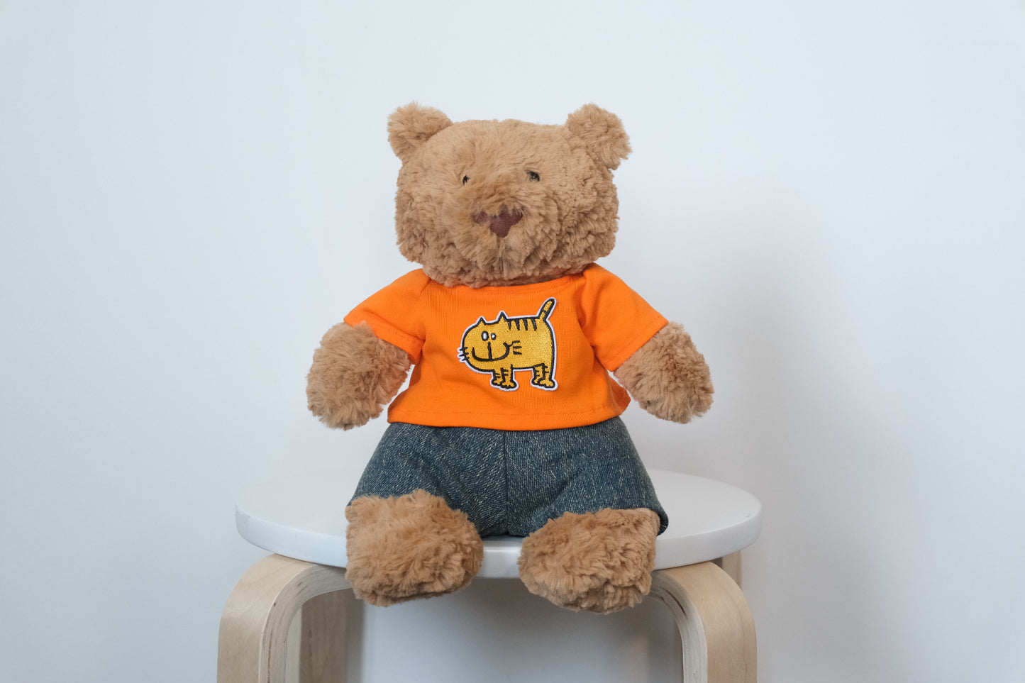 Jellycat Bartholomew Bear plush wearing a classic 2-piece outfit with a white T-shirt and blue denim jeans