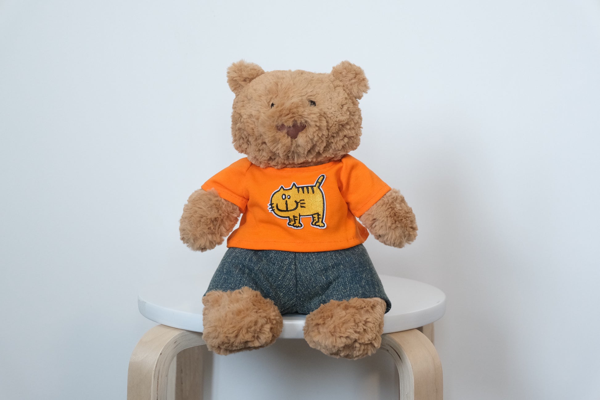 Jellycat Bartholomew Bear plush wearing a classic 2-piece outfit with a white T-shirt and blue denim jeans