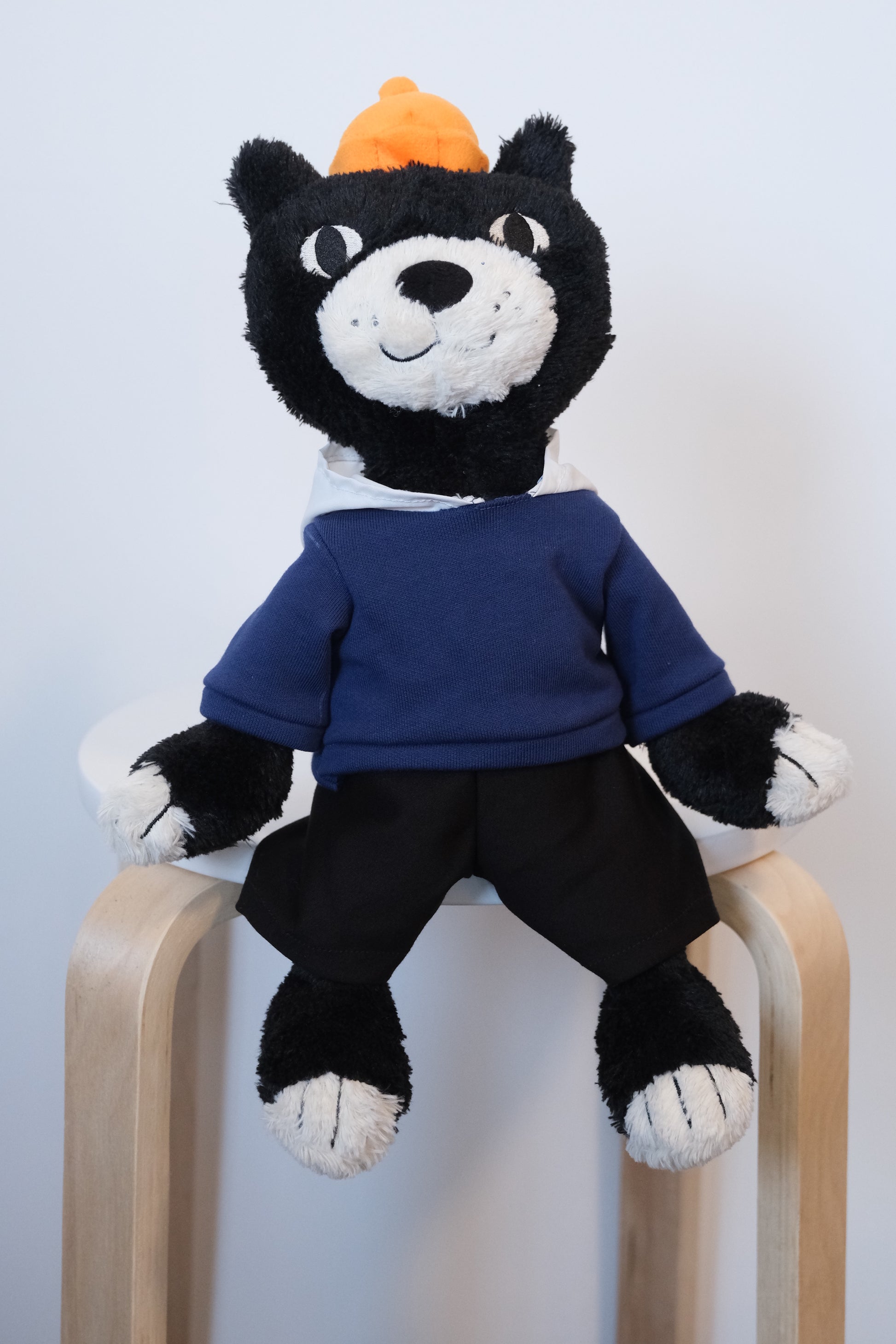 he official Jellycat Jack mascot cat plush wearing a blue streetwear hoodie and high-contrast white pants