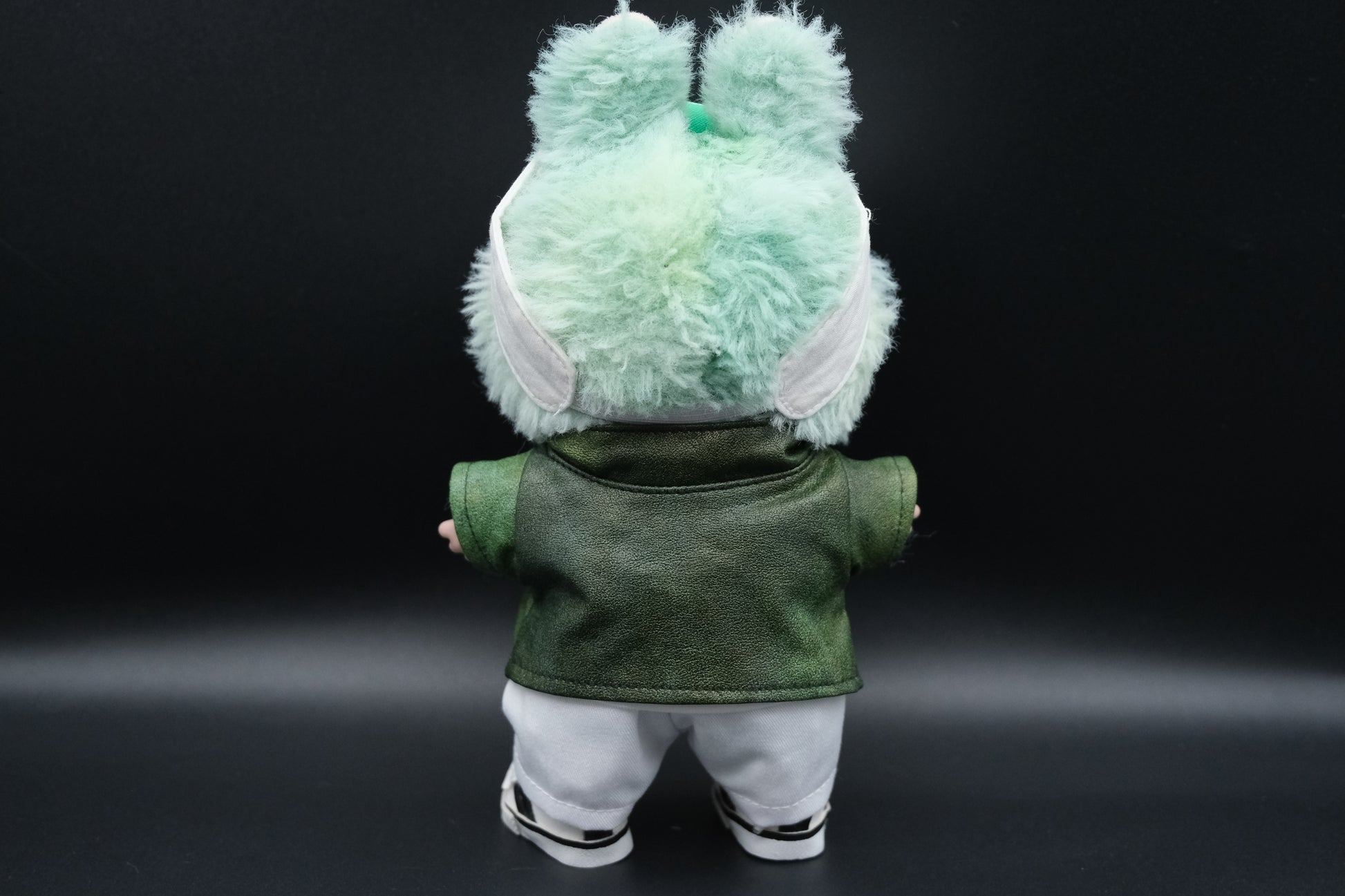 back view of A Labubu  wear a green leather jacket, white t-shirt, white pants, white shoes and cap
