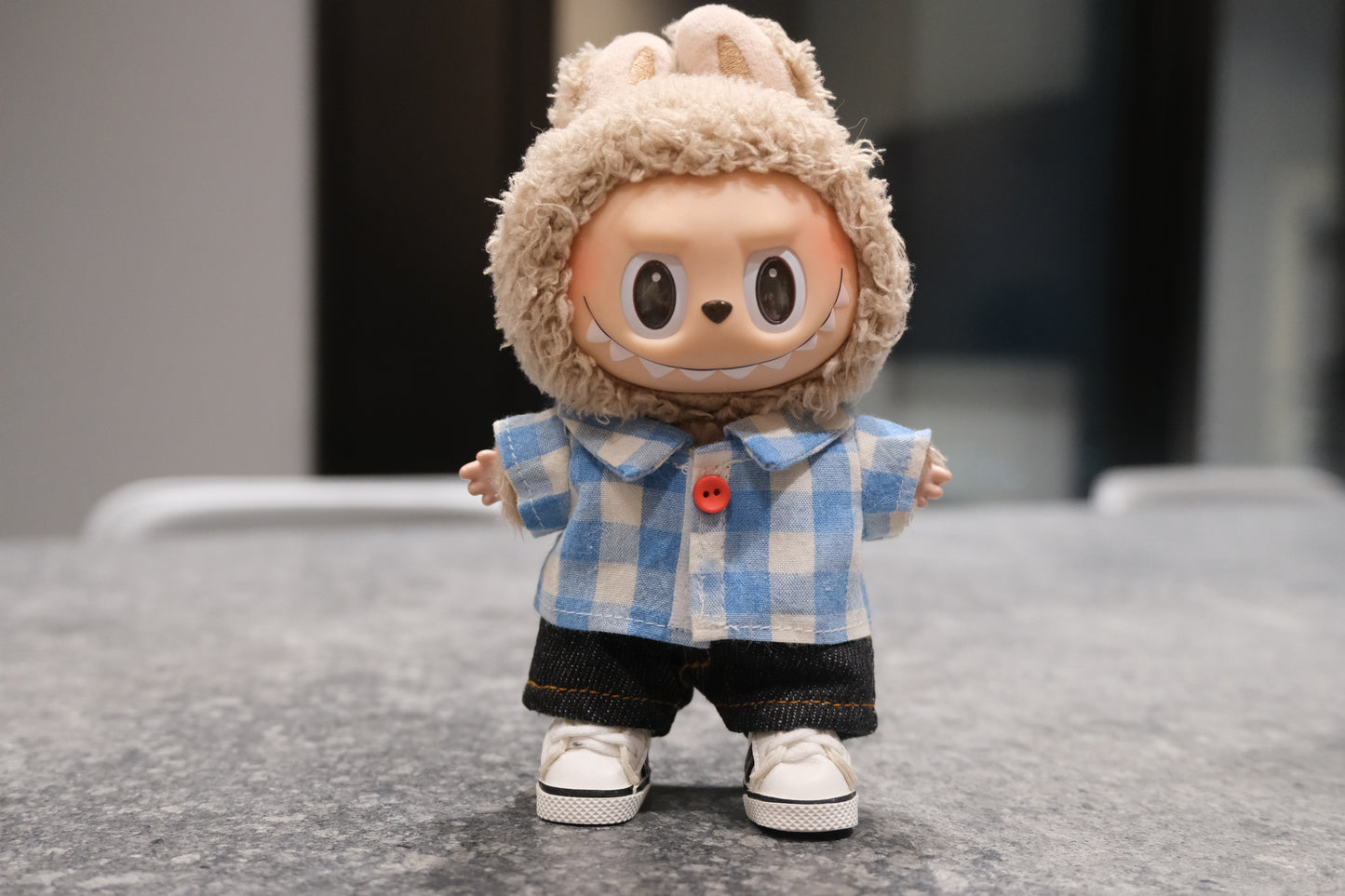 Labubu figure wearing a 3-piece casual outfit with a blue gingham shirt, dark denim shorts, and white sneakers