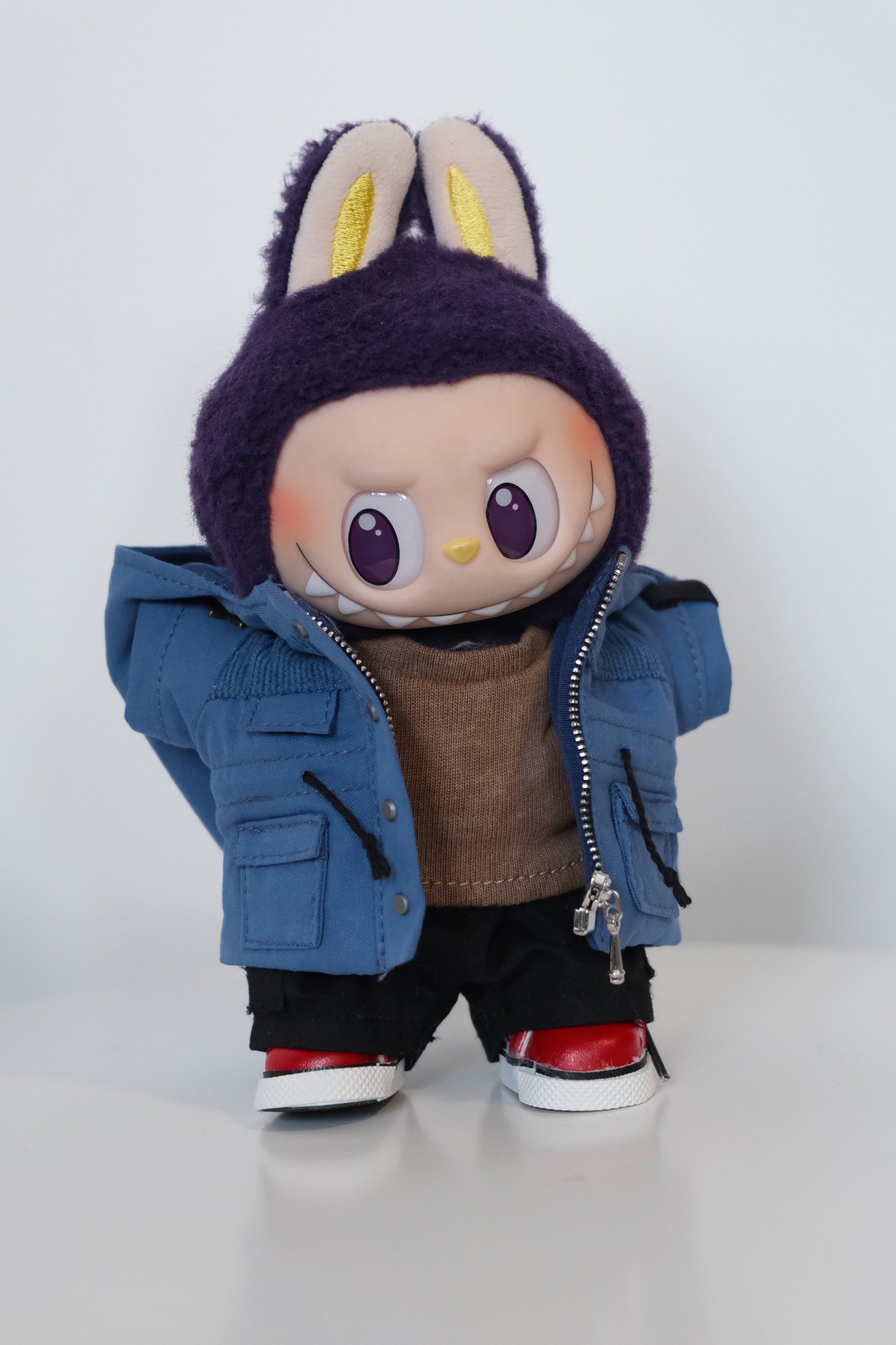 A Labubu figure dressed in a 4-piece blue winter mountaineering outfit, including a utility parka with a 'COOL' patch, black pants, and white sneakers.