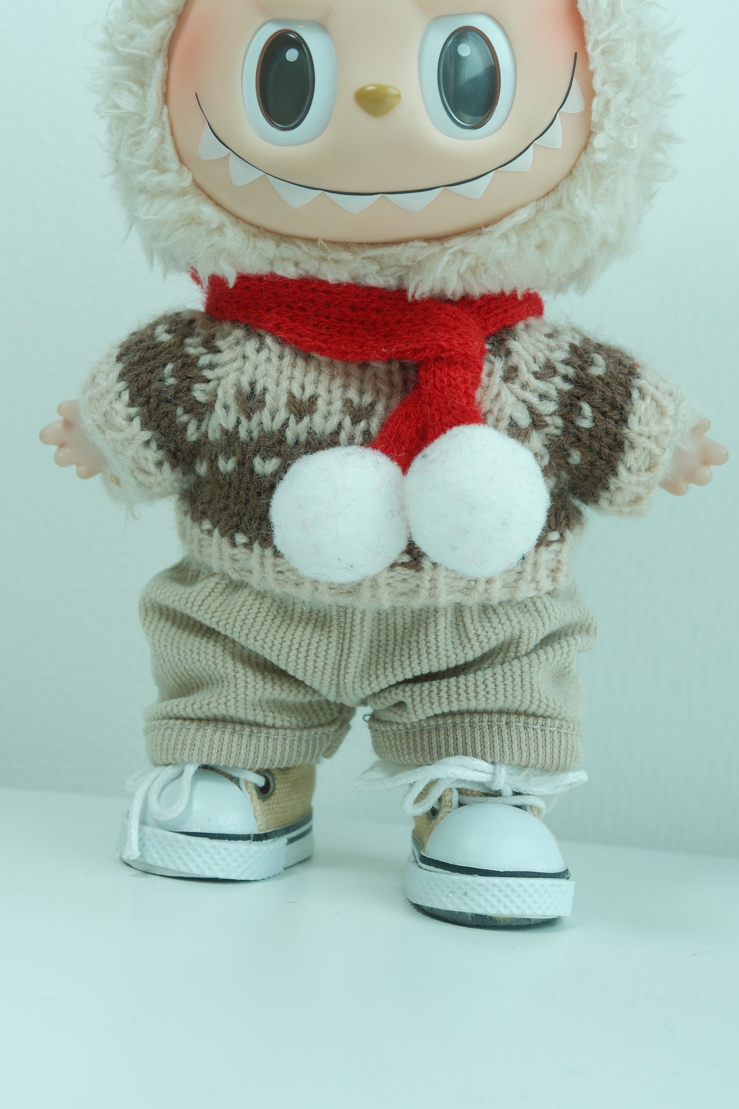 Labubu with a sweater, gloves, and a red Christmas scarf on a white background