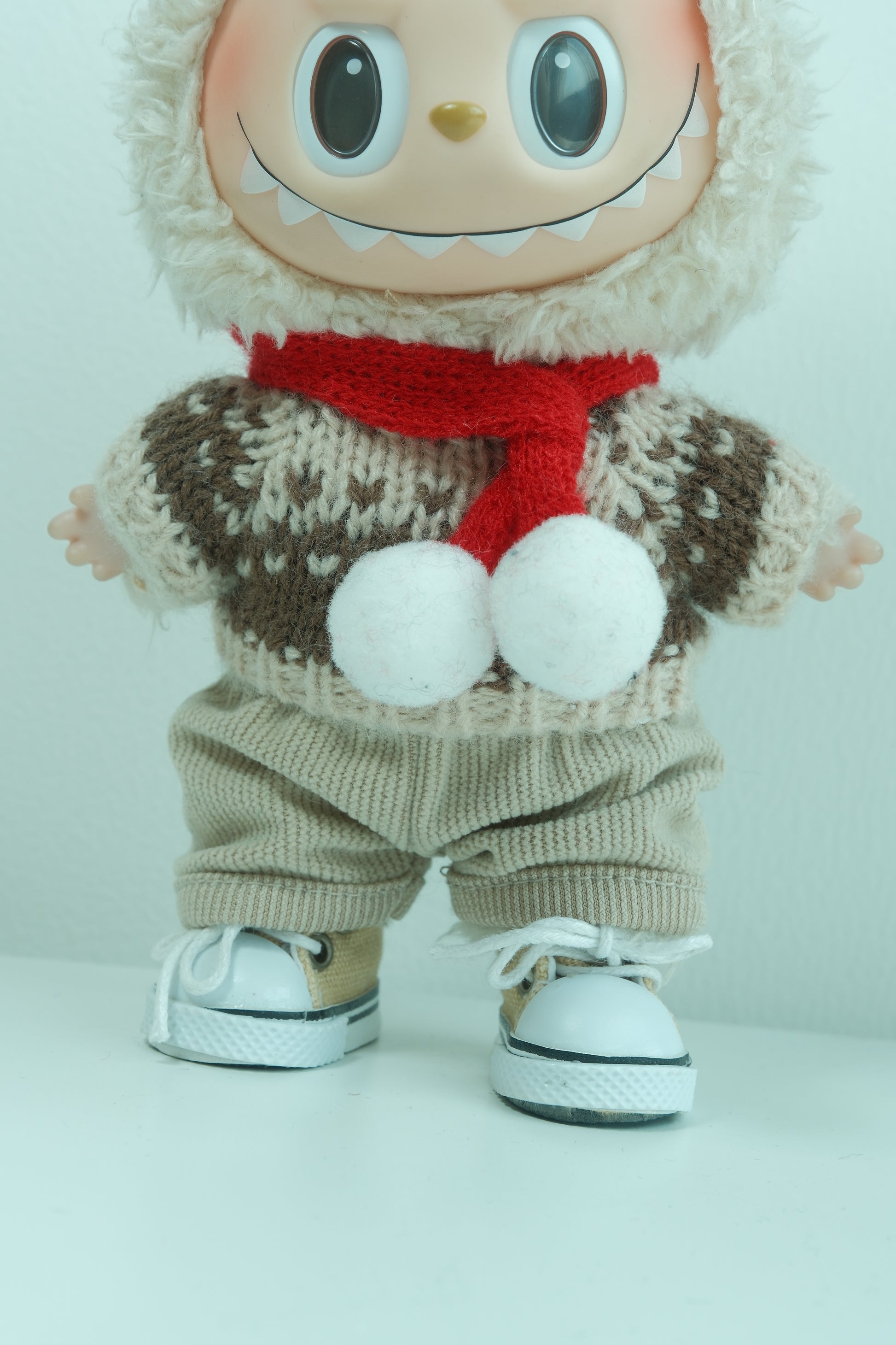 Labubu with a sweater, gloves, and a red Christmas scarf on a white background