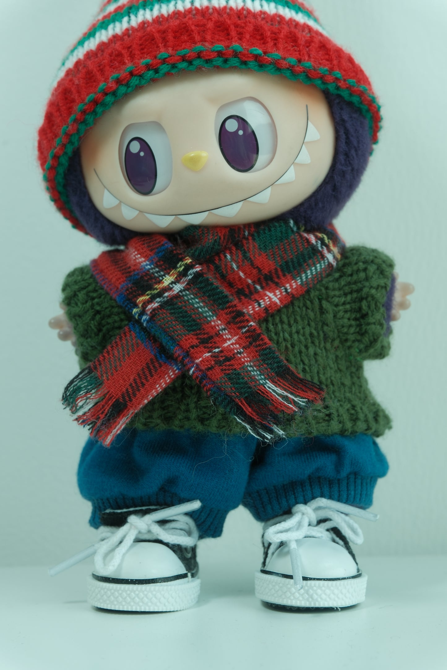 Close-up of labubu in the festive red, green, and hat and chunky green sweater