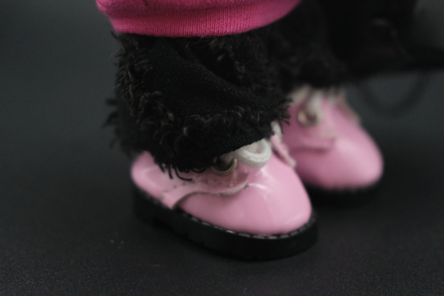 close-up of labubu's  pink shoes and black pants