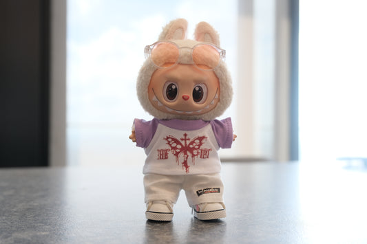 Labubu figure wearing a white and purple gothic butterfly graphic t-shirt, white pants, and sneakers with clear glasses