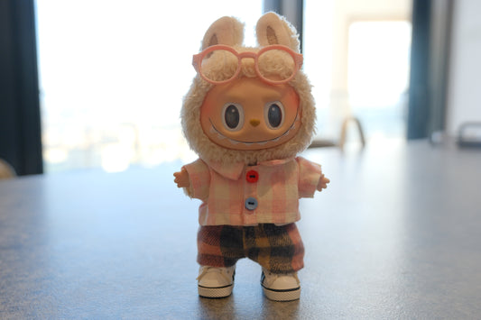 Labubu figure wearing a 4-piece outfit with a pink gingham shirt, dark plaid pants, white sneakers, and pink glasses