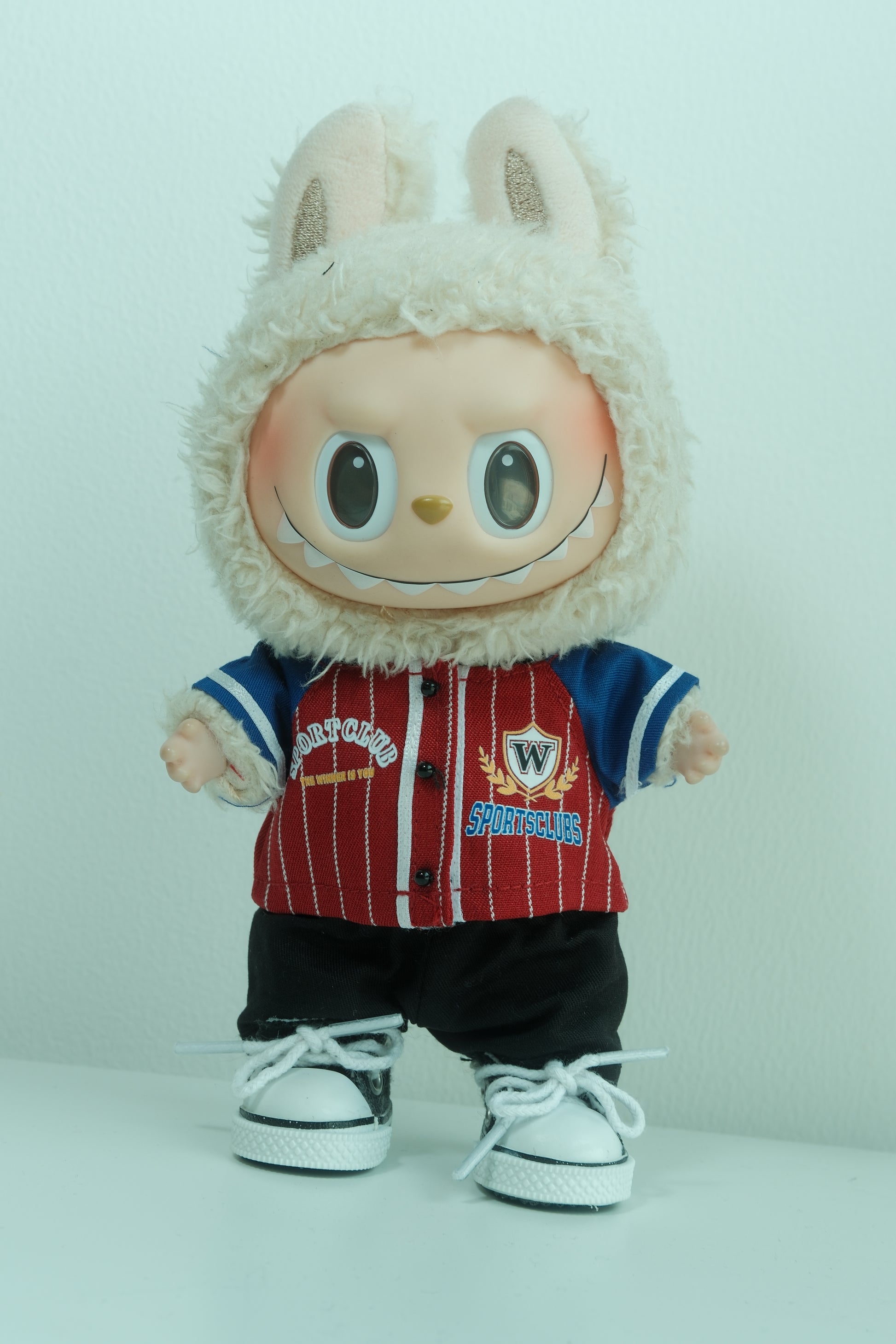 Labubu figure wearing a 3-piece casual streetwear outfit with a blue and white plaid shirt, light-colored pants, and white sneakers