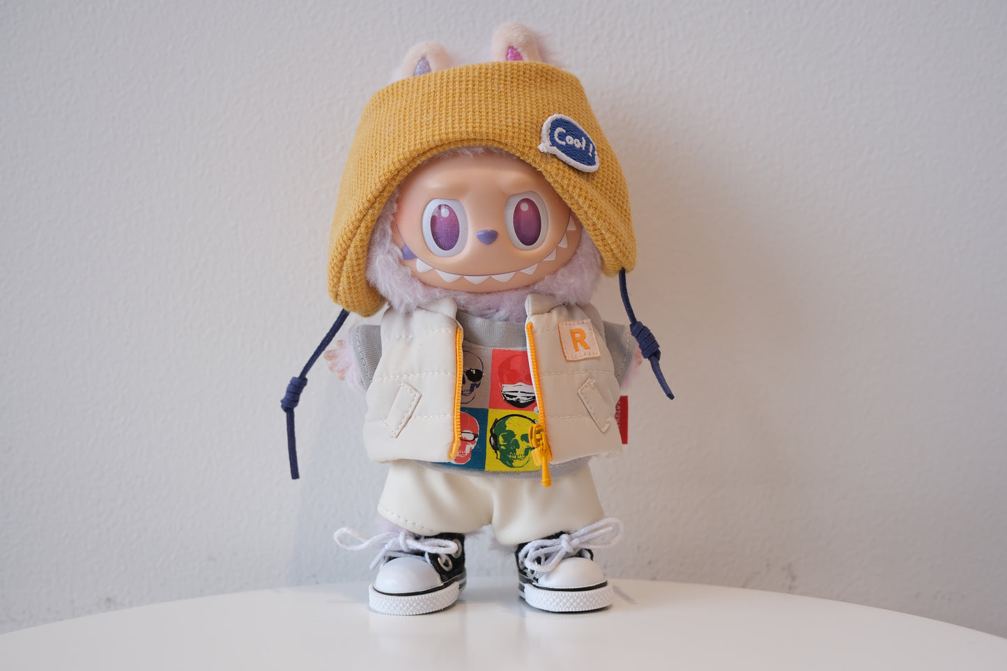labubu with a yellow hat and colorful backpack on a white surface