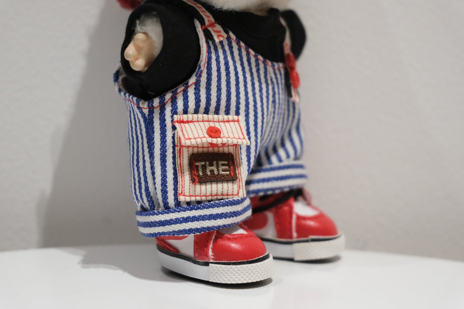 Close-up of labubu  figure in the pinstripe dungarees and black t-shirt.