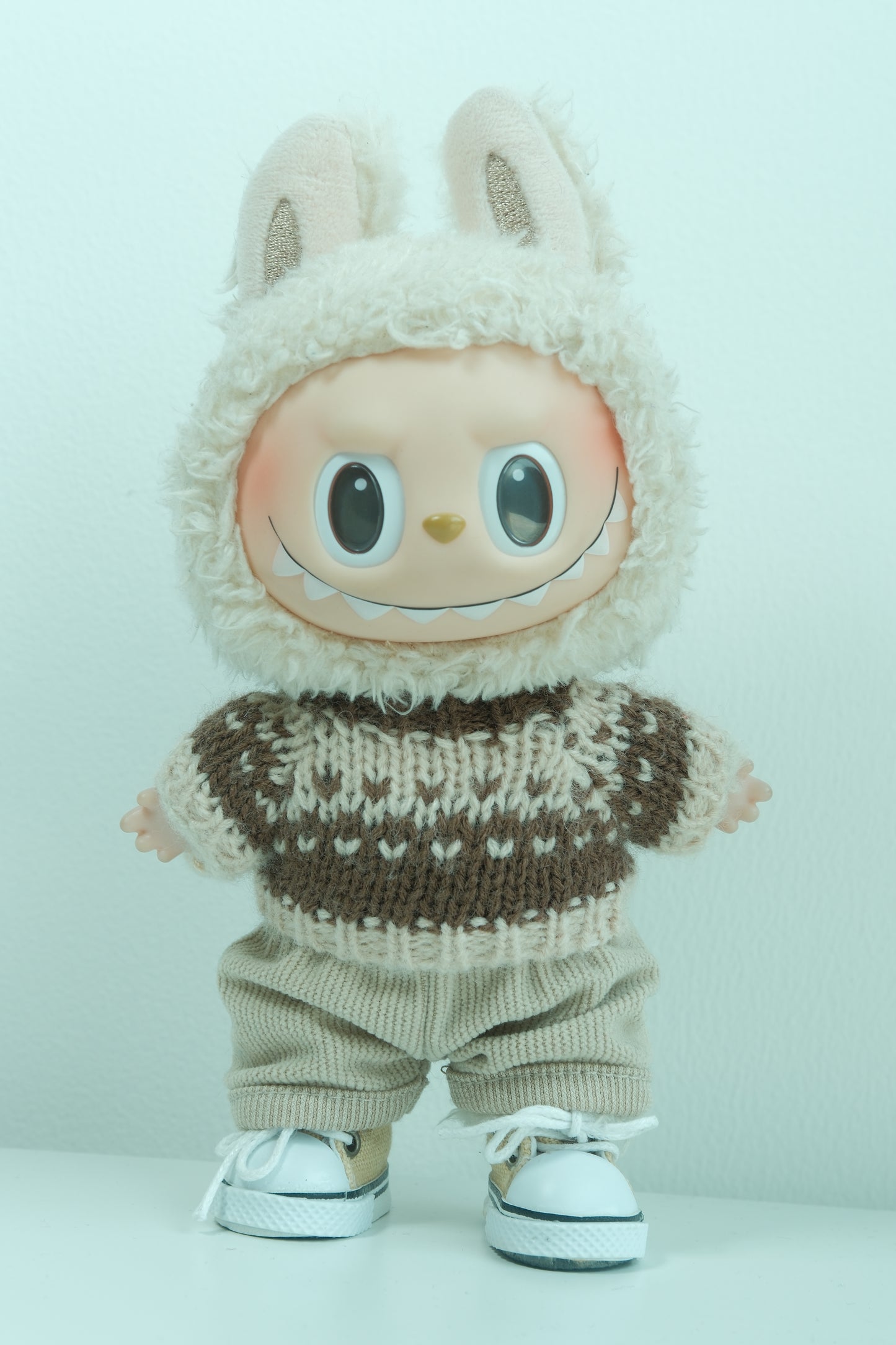 Labubu figure wearing a 3-piece rustic holiday outfit with a brown Fair Isle sweater, corduroy pants, and sneakers.