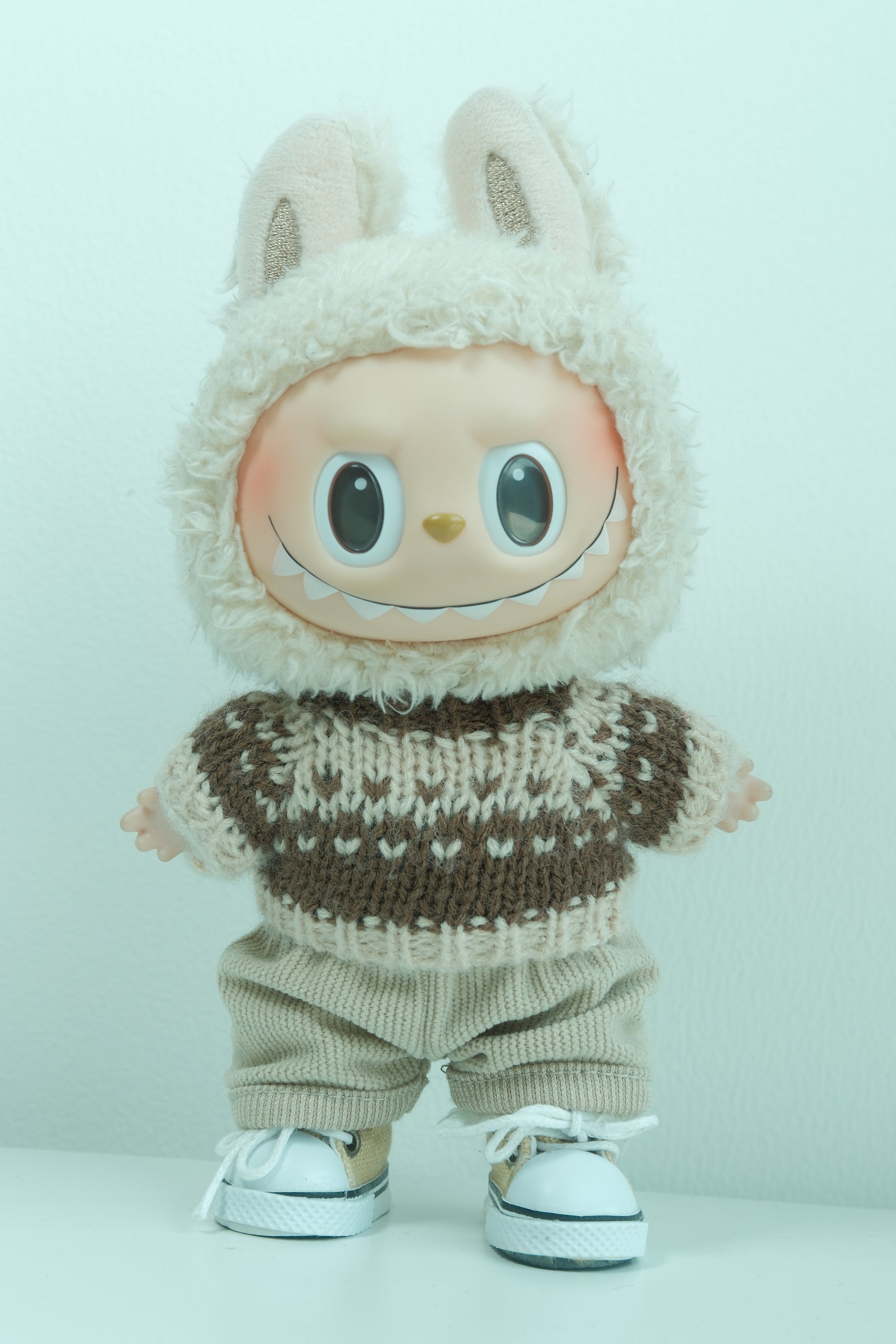 Labubu figure wearing a 3-piece rustic holiday outfit with a brown Fair Isle sweater, corduroy pants, and sneakers.