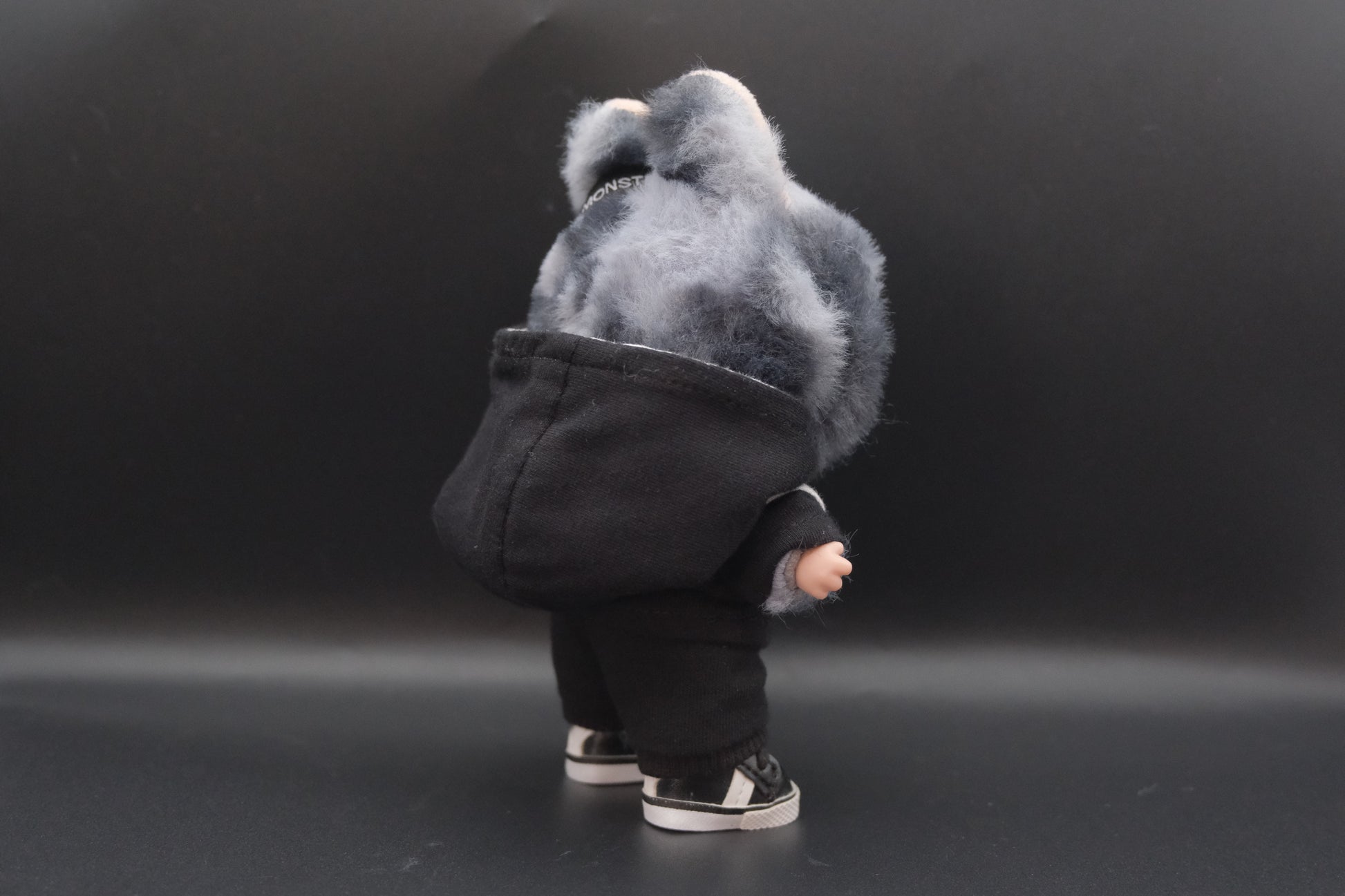 a back view of  A trendy Labubu designer toy figure wearing a black and white hoodei, pants and black shoes