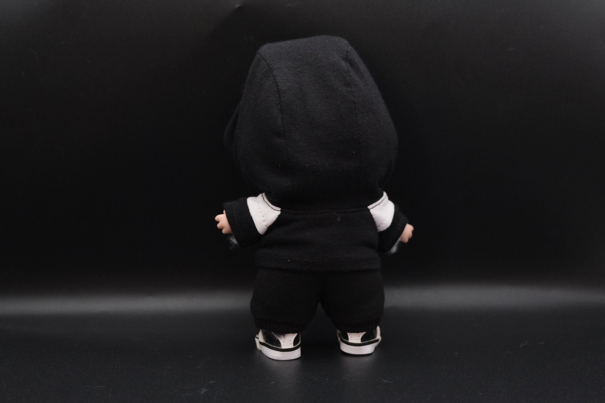 a back view of  A trendy Labubu designer toy figure wearing a black and white hoodei, pants and black shoes