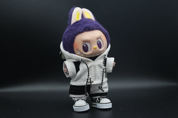 Front view of a Labubu art toy wearing a white hoodie with a skeleton ribcage graphic and a skeleton hand chain on the hood. The toy also wears black and white shorts and white high-top sneakers. Two silver cross necklaces hang from a black and white braided cord.