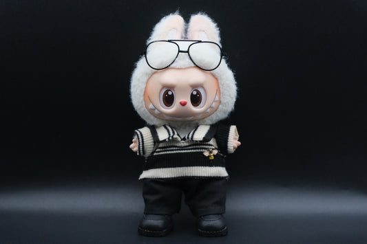 A Labubu figure wearing a white  and black color-blocked shirt, black pants,sunglasses and black sneakers.