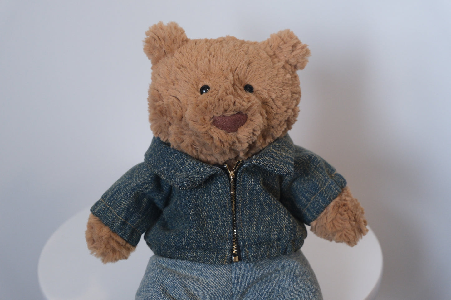 Close-up showing the yellow top-stitching and denim fabric texture on a miniature jacket for a Jellycat Bear.