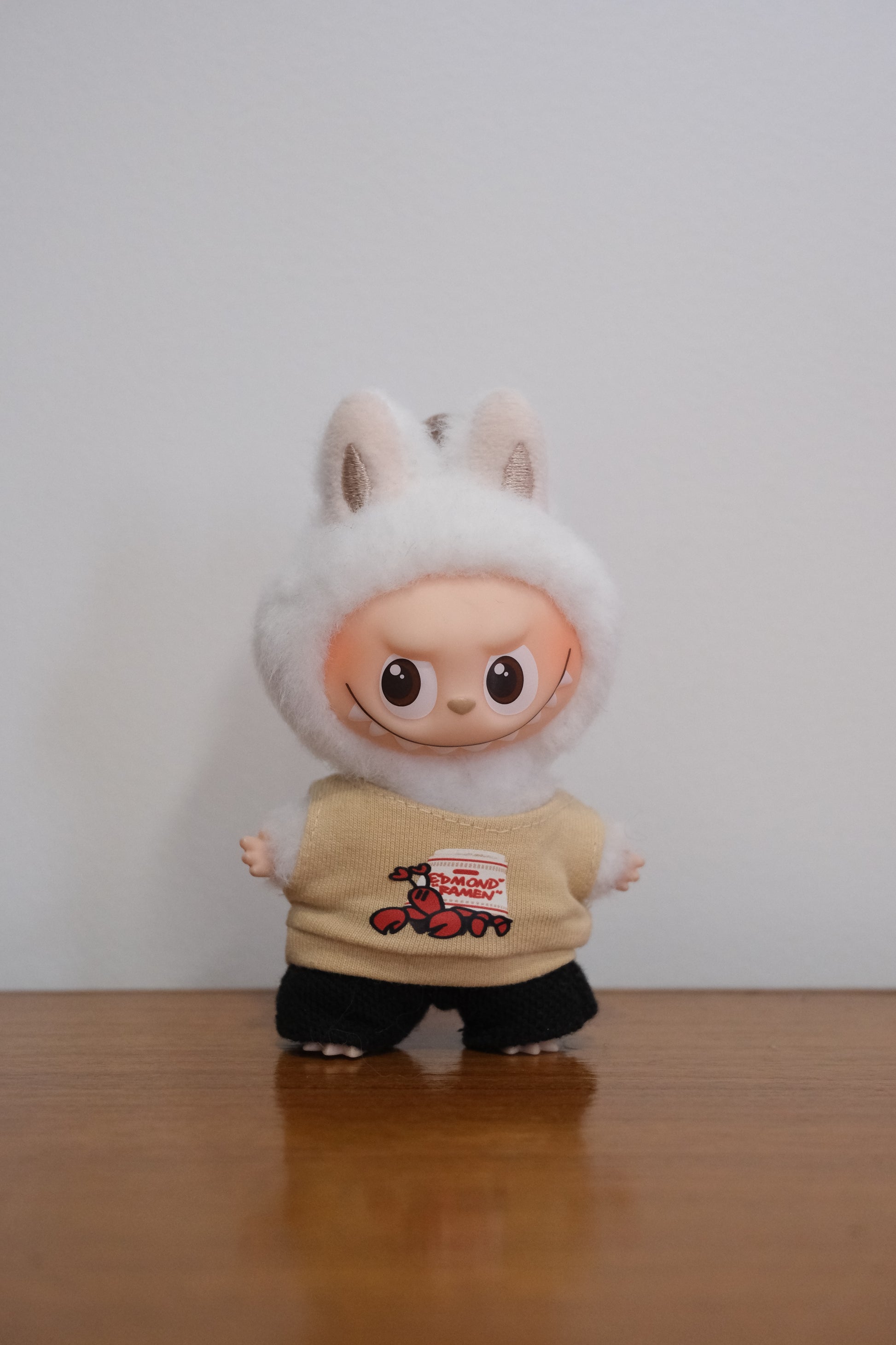 Labubu figure wearing a lobster graphic tank top and black pants.