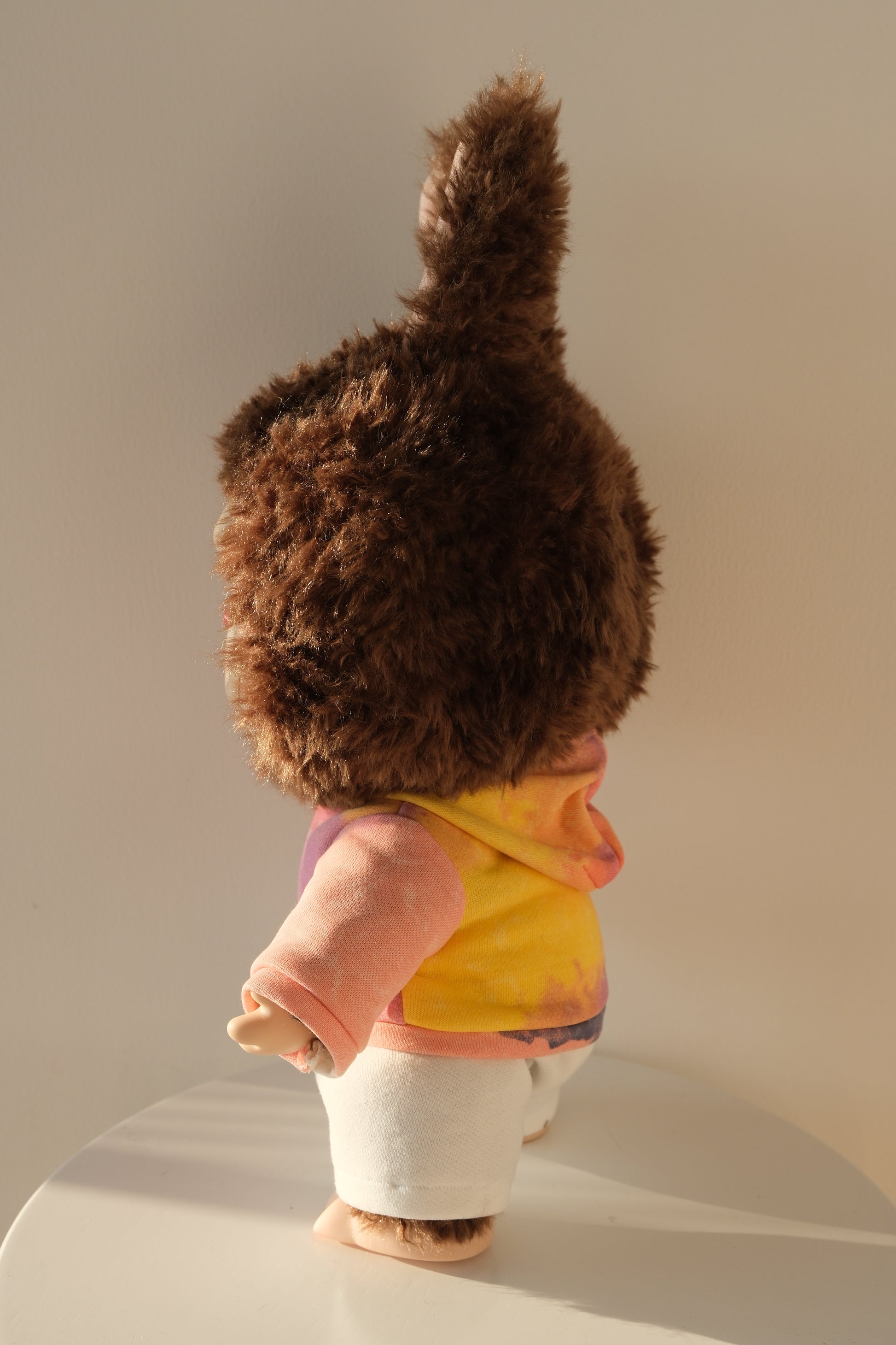 side view A 38cm Labubu figure wearing a vibrant gummy-colored neon hoodie and crisp white pants streetwear set