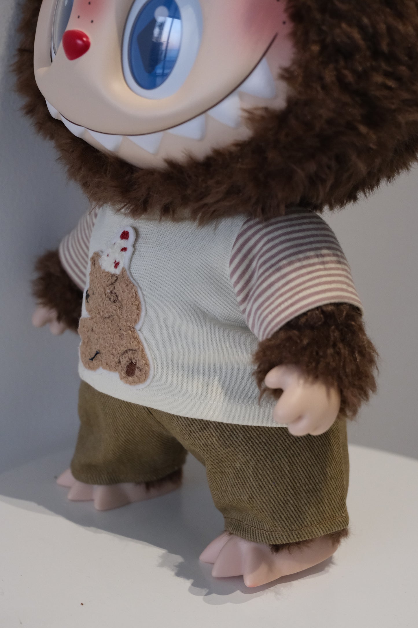 A cute Labubu figure dressed in a 2-piece child-style outfit from the Let's Checkmate series, featuring colorful paneled joggers and a playful graphic t-shirt.