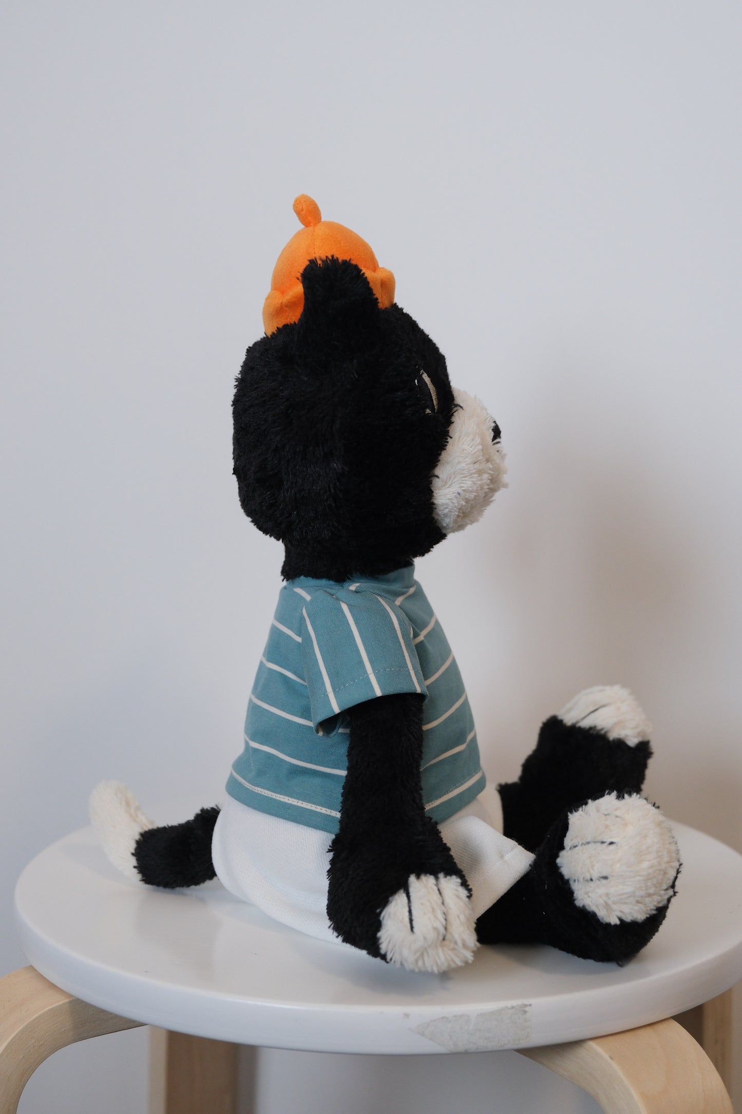 side view of jellycat jack wearing a striped shirt  a white pants