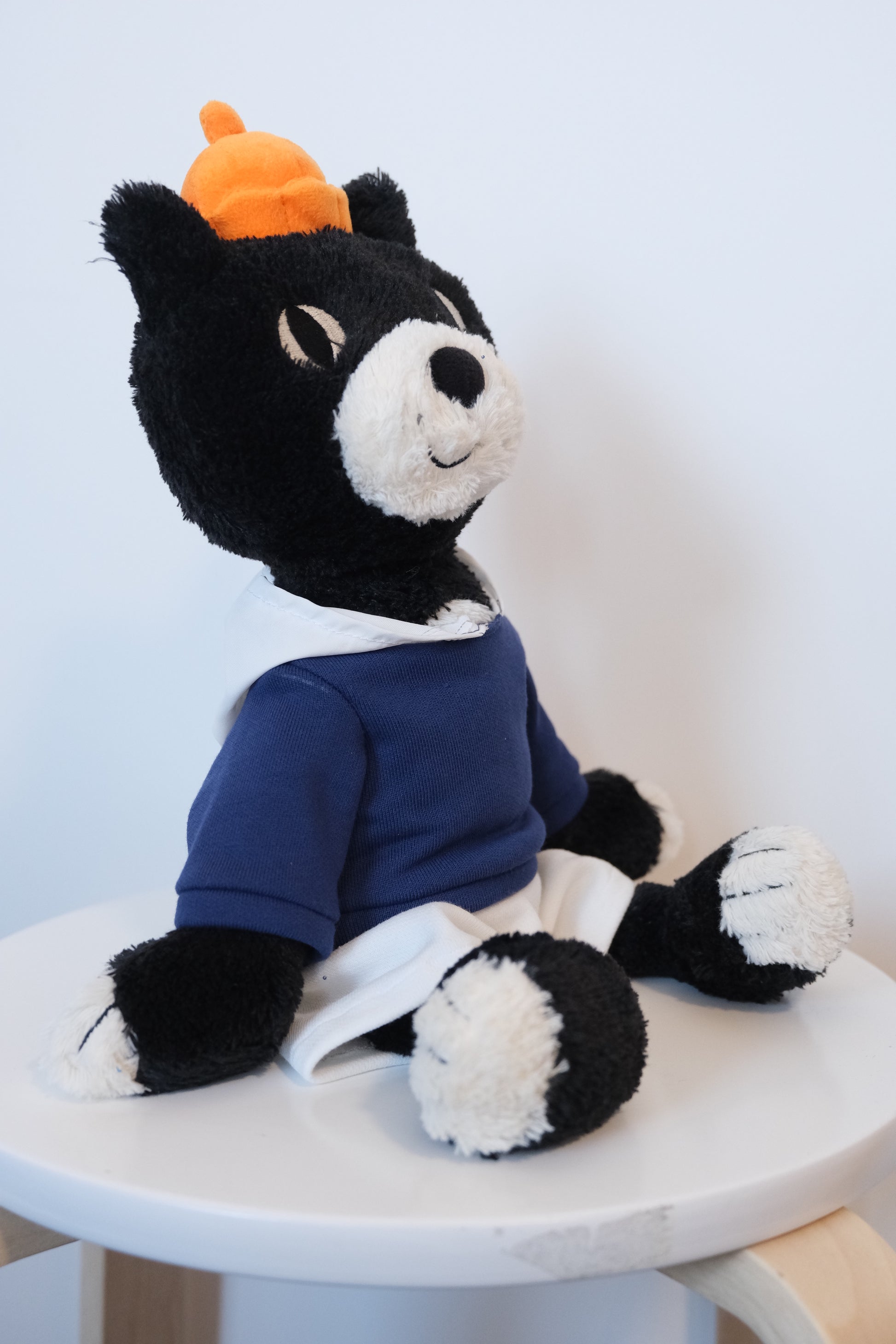 side view of Jellycat Jack mascot cat plush wearing a blue streetwear hoodie and high-contrast white pants.
