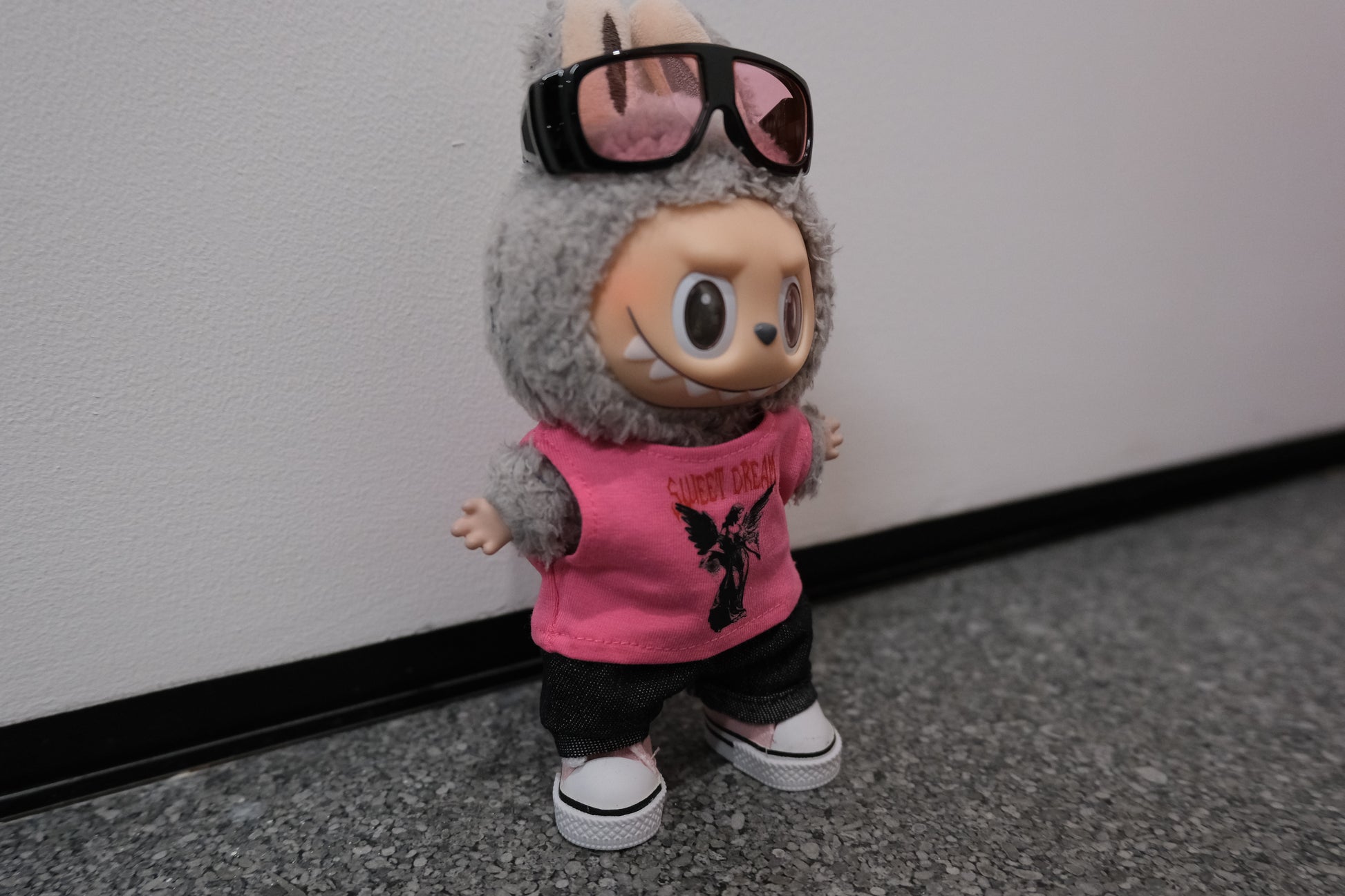 A Labubu figure wearing a 4-piece modern casual outfit, including a pink vest, denim jeans, sunglasses with a metallic frame, and pink sneakers.