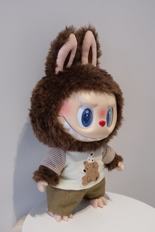 A cute Labubu figure dressed in a 2-piece child-style outfit from the Let's Checkmate series, featuring colorful paneled joggers and a playful graphic t-shirt