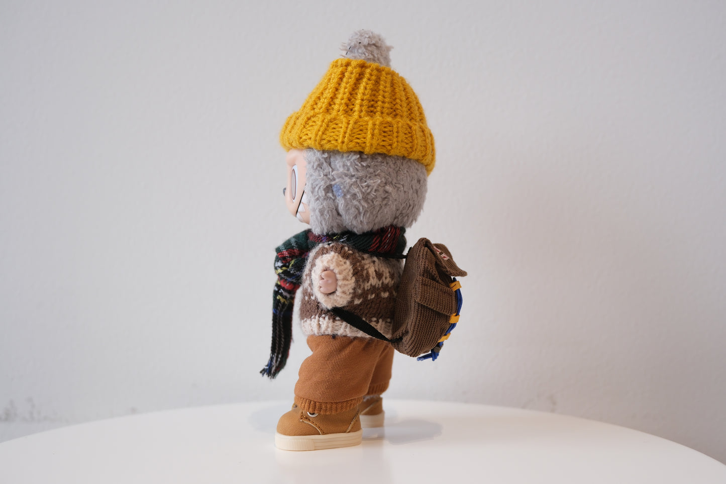 labubu with a yellow hat, scarf, and backpack on a white background