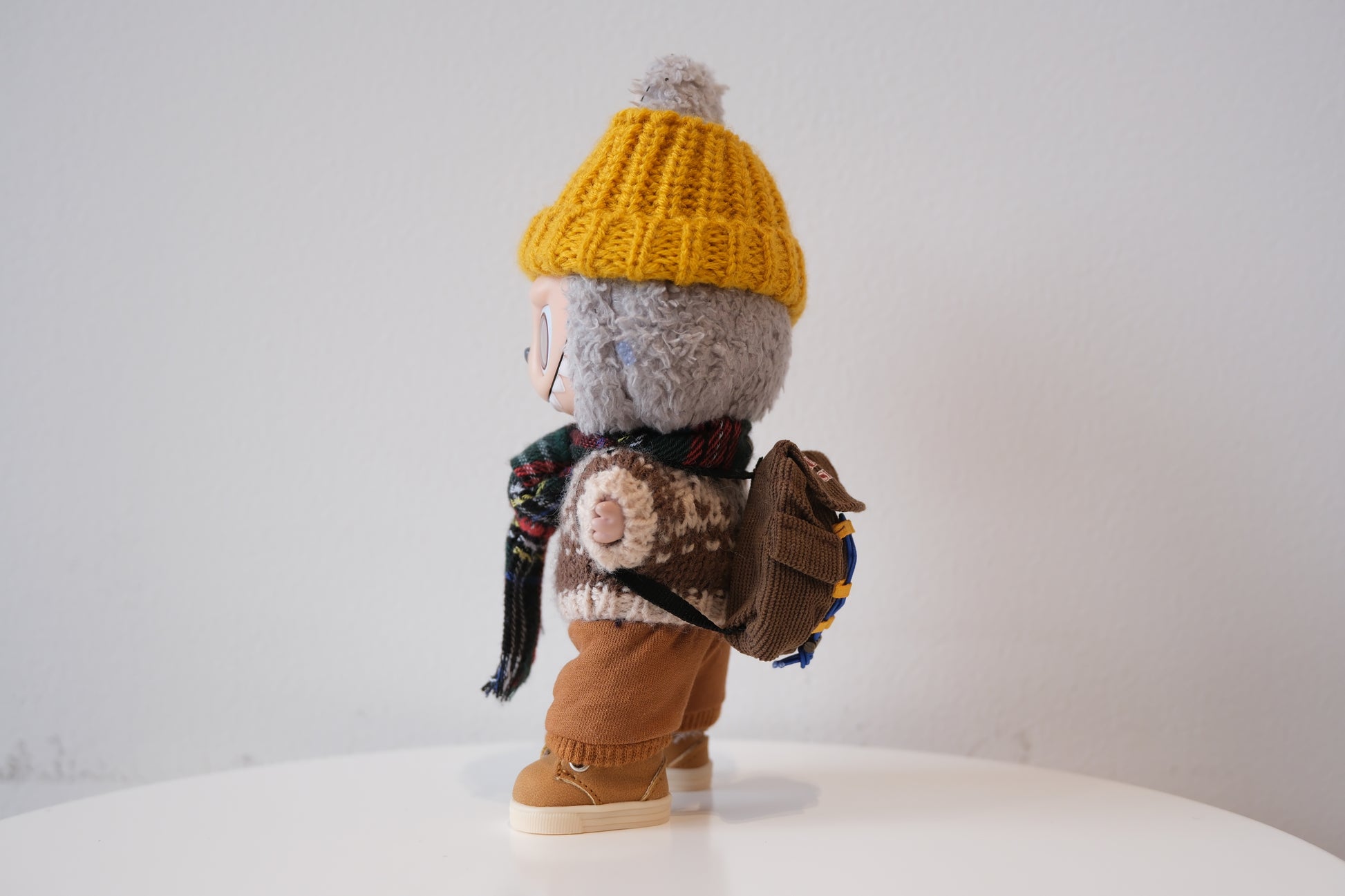 labubu with a yellow hat, scarf, and backpack on a white background