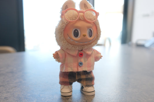 Labubu figure wearing a 4-piece outfit with a pink gingham shirt, dark plaid pants, white sneakers, and pink glasses