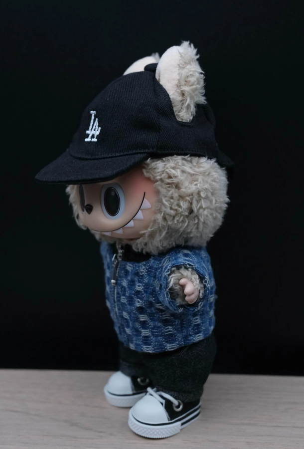 Labubu wearing a black cap with 'LA' logo and a blue jacket on a dark background