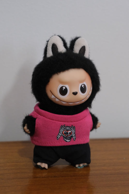 Labubu figure wearing a hot pink sweater with a skull and heart graphic