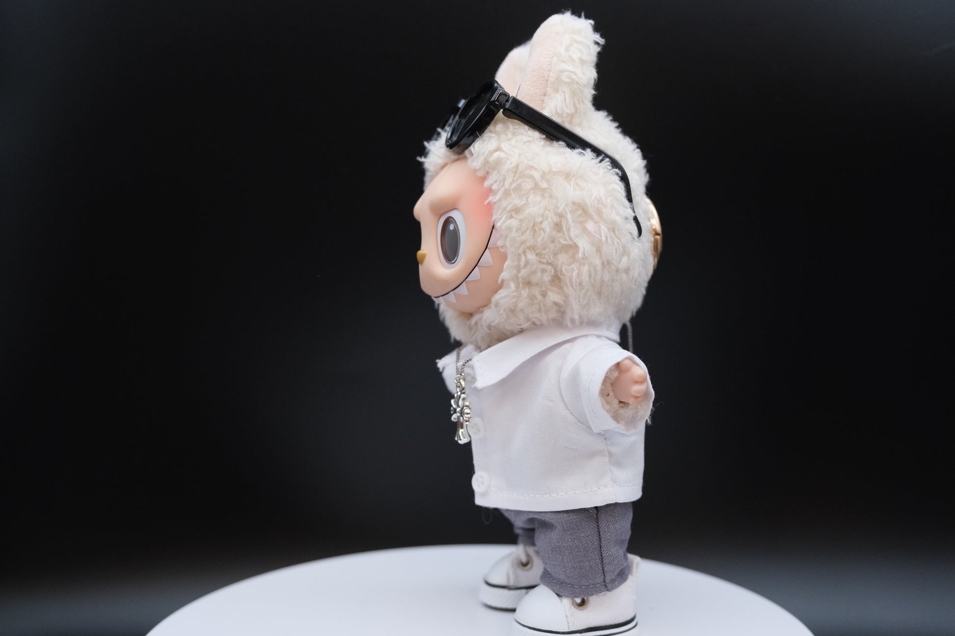 A Labubu figure wearing a 5-piece white outfit, including a shirt, sunglasses, necklace,shoes and pants.