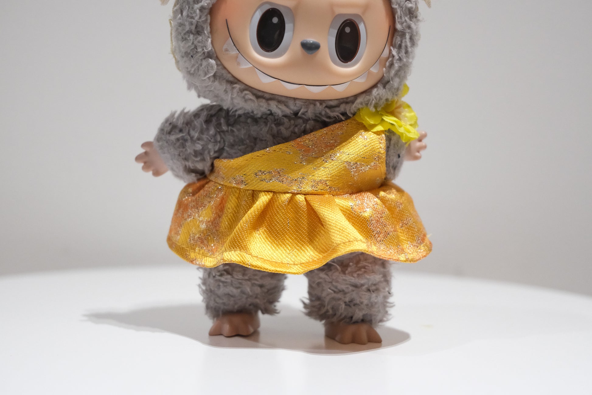 Close-up of The labubu figure's delicate pearl floral crown and shimmering yellow formal dress.