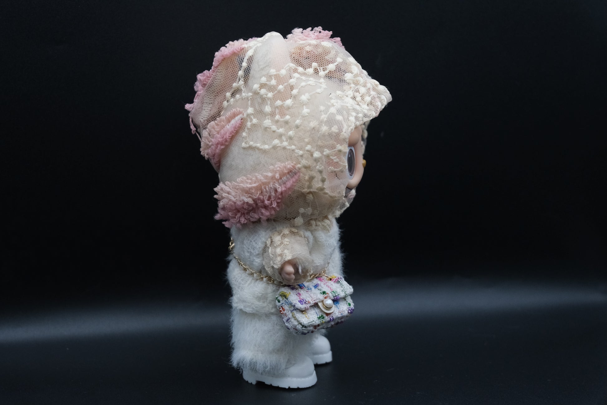 side view of A Labubu figure wearing a white designer hoodie outfit, white pants and shoes, and a crossbody bag